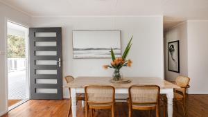 a dining room table with chairs and a vase of flowers at Walk To Beach, Pet Friendly Trampoline in Umina