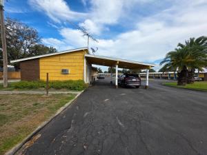 a yellow gas station with a car parked in it at Royal Inn in Kenedy