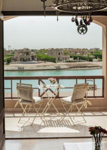 a table and chairs on a balcony with a view of the water at Nayah Stays, Cozy lagoons terrace one ensuite Apt in Hurghada