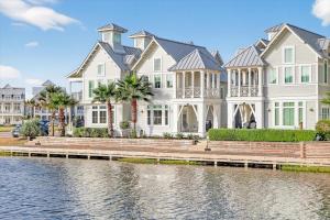 a large white house next to a body of water at Sun Chaser Cottage 205 FIV-D in Port Aransas