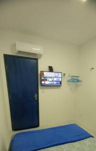 a room with a blue door and a tv at Cozinha e Lavadora Compartilhadas Qto e Wc privativos in São Luís