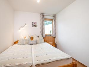 a white bed in a room with a window at Haus am Waldrand in Hopfgarten im Brixental