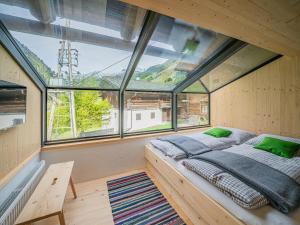 a bedroom with a bed in a room with windows at Raneburg 4 Almhaus in Matrei in Osttirol
