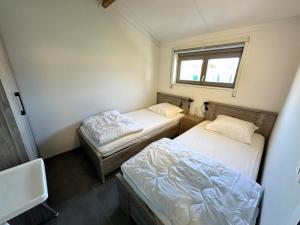 two beds in a small room with a window at Westhinder II H19 in Witte Burg