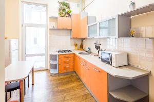 リヴィウにあるTwo Rooms Apart Prospekt Svobodyのキッチン(オレンジ色のキャビネット、シンク、テーブル付)