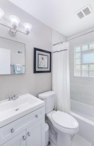 a white bathroom with a toilet and a sink at Designer 3BR Ranch Home near Clayton & Wash U in University City