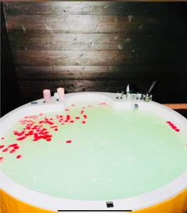a white bath tub with red petals on the floor at 南熱海長浜公園近くバーベキュー可能露天風呂付ゲストハウス in Taga