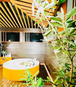 a bathroom with a yellow tub and some plants at 南熱海長浜公園近くバーベキュー可能露天風呂付ゲストハウス in Taga