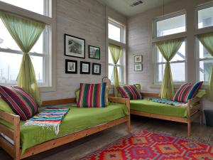 a living room with two green couches and windows at Beachfront Melody in Galveston