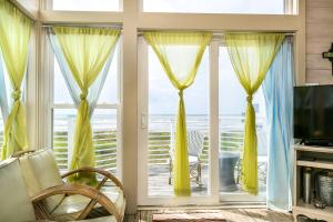 a living room with a window with yellow curtains at Beachfront Melody in Galveston +39 photos