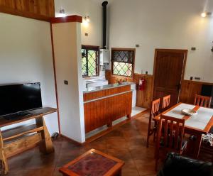 una cucina e una sala da pranzo con un tavolo e una televisione di Cabañas Alto Caburgua a Caburgua