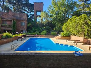 una piscina en un patio con bancos y una casa en Tiempo Compartido Clermont Pinamar, en Pinamar