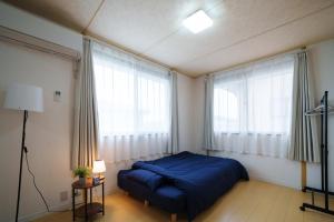 a bedroom with a blue bed and large windows at コルネット館山 in Tateyama