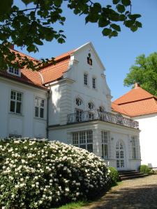 a white house with a balcony and flowers at Schloss Badow in Badow