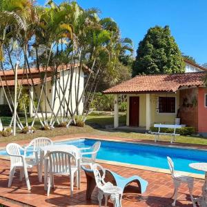 un patio avec une table et des chaises à côté d'une piscine dans l'établissement Chalés Paraíso Verde, à Itatiaia