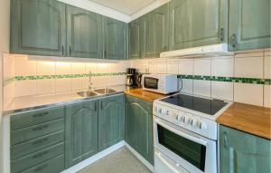 a kitchen with green cabinets and a white stove top oven at 2 Bedroom Nice Home In Byxelkrok in Byxelkrok