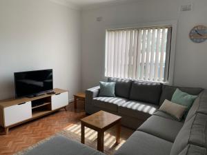 a living room with a couch and a flat screen tv at Coconut Cottage by Book Jervis Bay - Sanctuary Point in Sanctuary Point