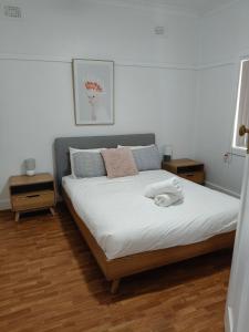 ein Schlafzimmer mit einem großen Bett mit weißen Laken und Kissen in der Unterkunft Coconut Cottage - Sanctuary Point in Sanctuary Point