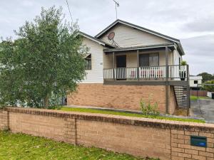 a house with a balcony on a brick wall at Coconut Cottage by Book Jervis Bay - Sanctuary Point in Sanctuary Point