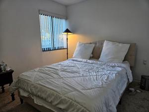 a bedroom with a bed with white sheets and a window at Elegance in Alexandria