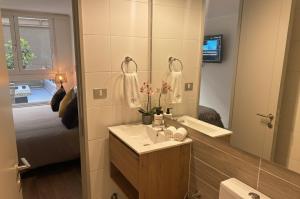 Un baño con lavabo, espejo y cama. en Santiago Centro I Eventos Movistar Arena, en Santiago