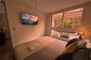 Un dormitorio con una cama y un televisor y una ventana. en Santiago Centro I Eventos Movistar Arena, en Santiago