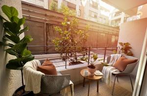 Un balcón con dos sillas y una mesa y plantas. en Santiago Centro I Eventos Movistar Arena, en Santiago