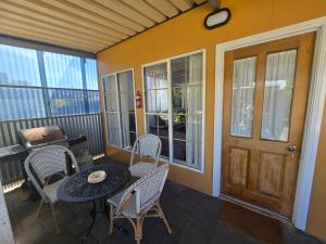 a porch with a table and chairs and a door at Contemporary Studio Accommodation in Farrell Flat