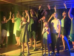 Un grupo de personas cantando en un escenario con las manos en alto. en Chalet confortable de 35m² avec Terrasse - API-1-52-488, en Le Fouilloux