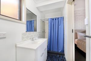 a bathroom with a sink and a blue shower curtain at Boggabri Motel in Boggabri +34 photos