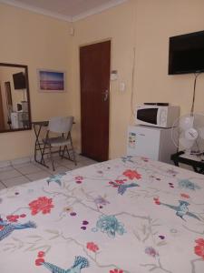 a bedroom with a bed with a flowered blanket on it at Yana House in Polokwane