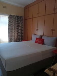 a bedroom with a large white bed with a red pillow at Yana House in Polokwane