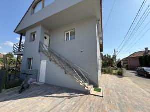 a white house with a staircase on the side of it at Bee house 12 in Odorheiu Secuiesc