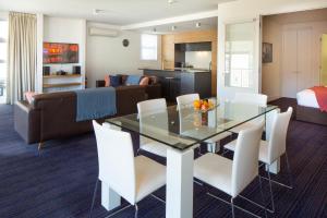 a dining room and living room with a glass table and white chairs at Lakeside Retreat Three Bedroom Apartment- 303 in Frankton Wharf