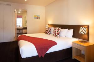a bedroom with a large bed with a red blanket on it at Lakeside Retreat Three Bedroom Apartment- 303 in Frankton Wharf