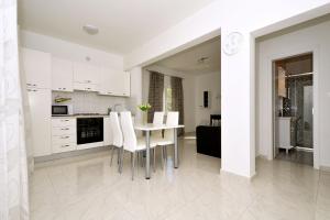 eine Küche mit weißen Schränken und einem Tisch und Stühlen in der Unterkunft Seaside holiday house Vinisce, Trogir - 16488 in Vinišće + 5 Fotos