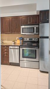 a kitchen with stainless steel appliances and wooden cabinets at Lux suite - City View - Steps to Rogers Centre & CN Tower in Toronto