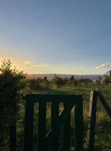 une porte verte dans un champ avec le coucher du soleil en arrière-plan dans l'établissement La Colorada de Yacanto, à Villa Yacanto