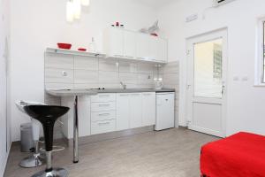 a kitchen with white cabinets and a table and a stool at Apartments by the sea Ston, Peljesac - 10226 in Mali Ston +19 photos