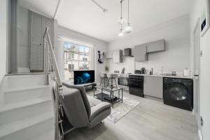 a living room with a chair and a kitchen at CLG Apartments Near Paddington Station & Hyde Park in London