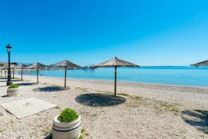 a sandy beach with umbrellas and the water at Apartments by the sea Vir - 24953 in Vir