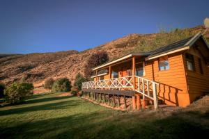 a wooden house with a hill in the background at Nahuel Mapi Lodge in Pilolil