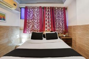 アーメダバードにあるHotel O Kanchan Palaceのベッドルーム1室(赤いカーテン付きの大型ベッド1台付)