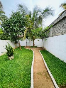 a garden with palm trees and a white wall at Samara Beach Stay in Weligama