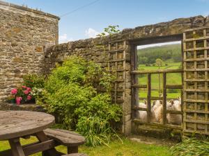 an old wooden gate in a stone wall with a picnic table at The Shippon in Appletreewick