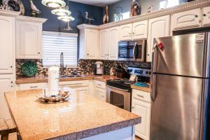 Una cocina con gabinetes blancos y un refrigerador de acero inoxidable. en SEA DREAMS 3 condo, en South Padre Island