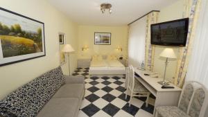 ein Wohnzimmer mit einem Sofa und einem Schreibtisch in einem Zimmer in der Unterkunft Hotel Anika in Neuenburg am Rhein