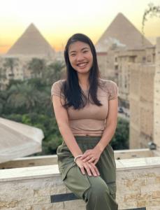 a woman sitting on a wall with pyramids in the background at Kings of the ancient pyramids in Cairo