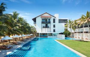 ein Hotelpool mit Palmen und ein Gebäude in der Unterkunft Jetwing Blue in Negombo