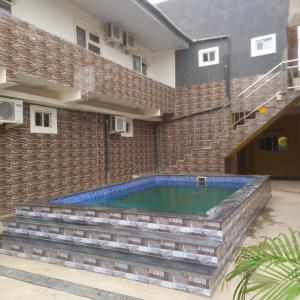 a swimming pool in front of a brick building at Lá Maison Jolly in Luanda